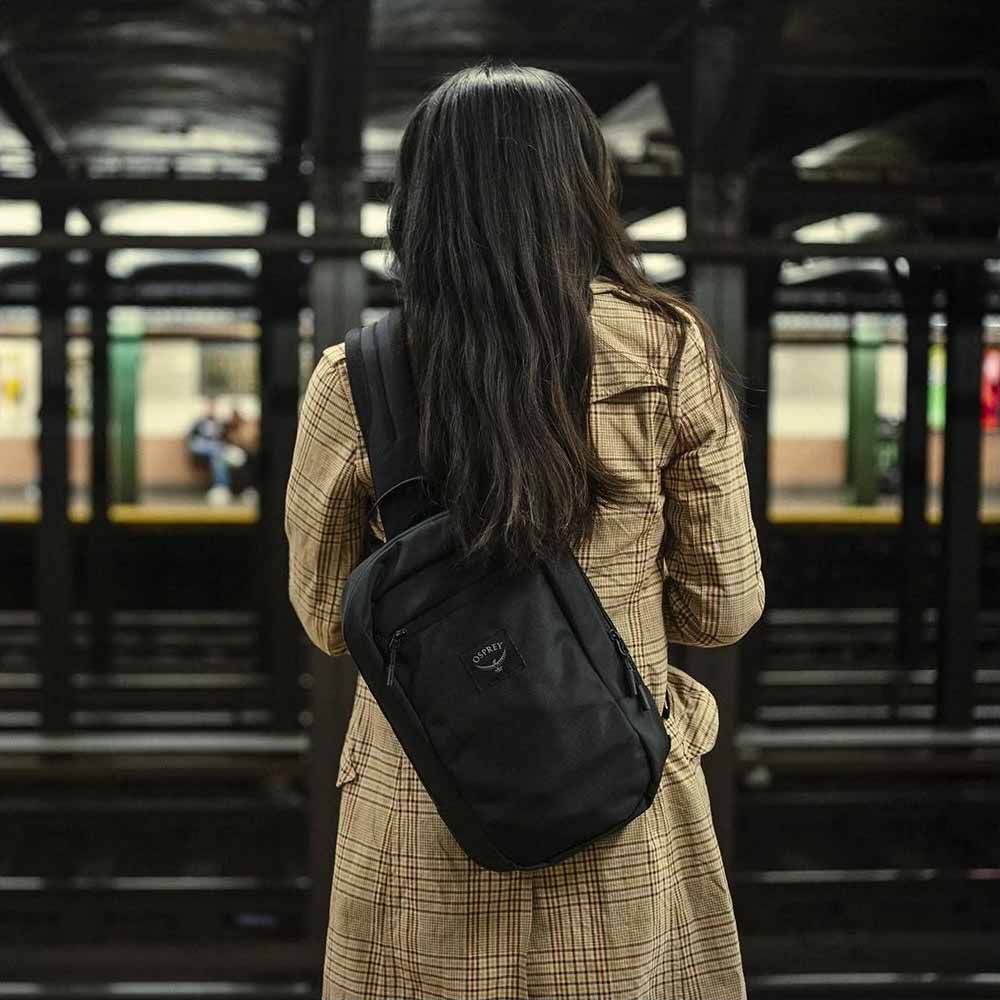 en model bruger Osprey Aoede Sling skuldertaske (unisex) på en metro