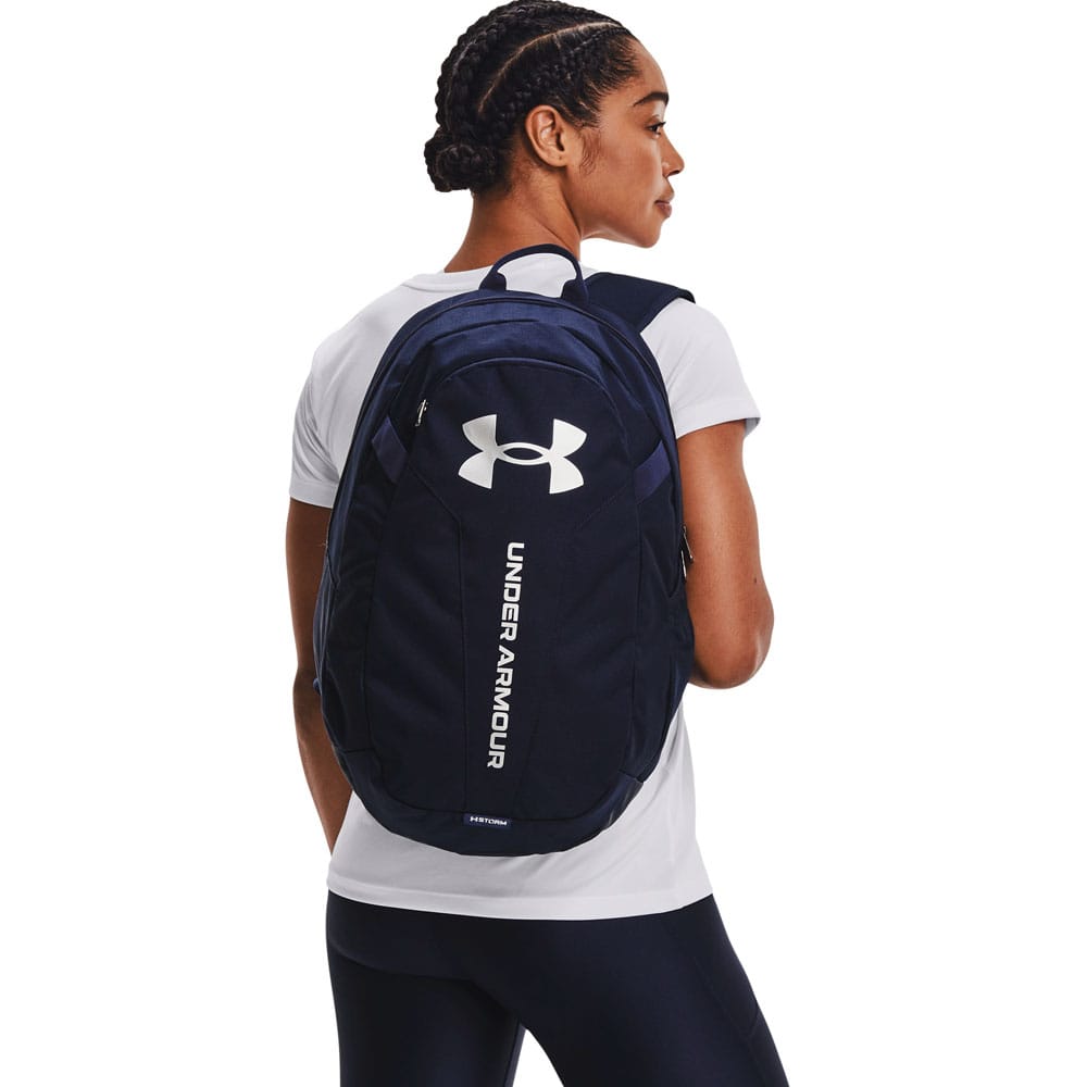 En model bærer en Under Armour Hustle Lite hverdagsrygsæk (unisex)