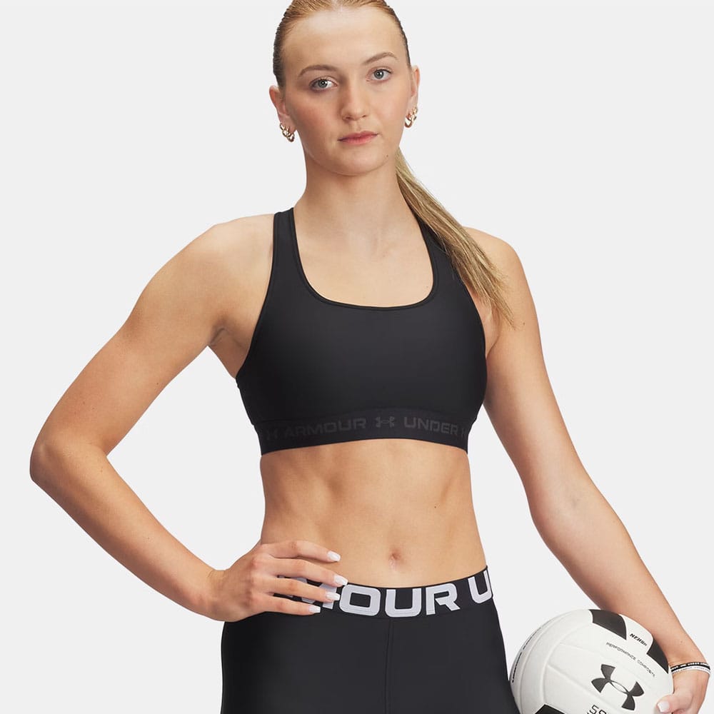 en model har en sort Under Armour Cross Back Mid Bra sports-bh (dame) på
