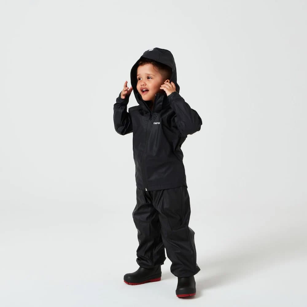 Dreng står med siden mod kameraet iført Tretorn Kids Packable rainset i farven jet black