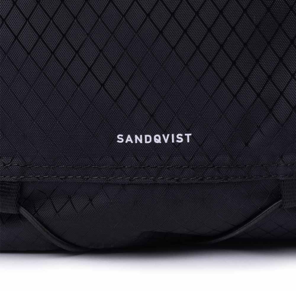 Logo på forsiden af nærbillede af inderlomme på Sandqvist Nils