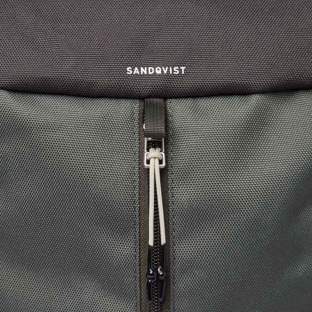 Nærbillede af Sandqvist Sune-logo og lynlås.