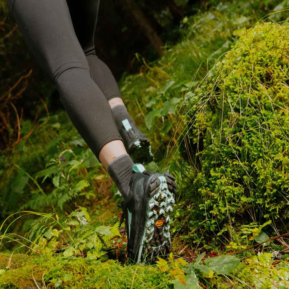 malli käyttää Altra Lone Peak 9+ maastojuoksukenkiä (naiset) metsässä