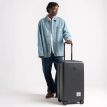 henkilö pitelee Herschel Heritage Hardshell Medium Luggage 67 L matkalaukkua (unisex)